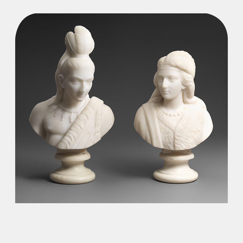 Two white marble statues of a man and a woman side by side.